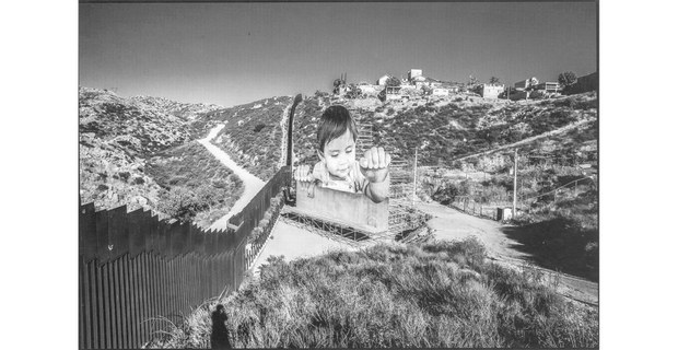 En el lado mexicano del muro, el artista francés JR levantó la figura de un niño agarrándose de la pared y mirando por encima de ella. Tecate, Baja California, 2017. Foto: David Bacon